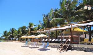 a group of chairs and umbrellas on a beach at Pousada Paraiso da Barra in Barra de Santo Antônio