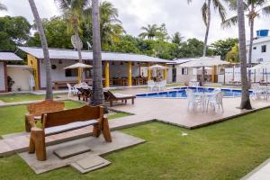 a backyard with a pool with a bench and tables at Pousada Paraiso da Barra in Barra de Santo Antônio
