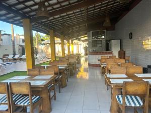 an empty restaurant with wooden tables and chairs at Pousada Paraiso da Barra in Barra de Santo Antônio