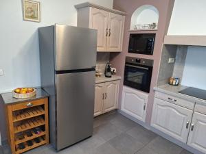a stainless steel refrigerator in a kitchen with white cabinets at Gîte du Craon de Ludes in Ludes