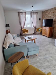 a living room with a couch and chairs and a tv at Gîte du Craon de Ludes in Ludes