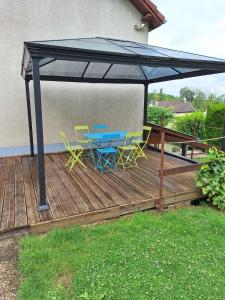 a picnic table and chairs under a canopy on a deck at Gîte du Craon de Ludes in Ludes