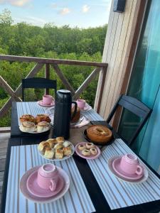 a table with pastries and tea pots and plates of food at Recanto Paraiso Tropical- Praia Ajuruteua in Bragança +12 photos