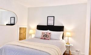 a white bedroom with a bed with a pink pillow at Secret City Cottage - Peaceful - Private Garden in Aberdeen