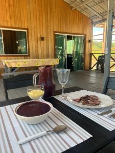 a table with a bowl of chocolate pudding and a plate of bacon at Recanto Paraiso Tropical- Praia Ajuruteua in Bragança