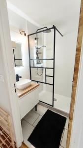 a bathroom with a sink and a glass shower at Charmant Appartement Les temples du Soleil in Font-Romeu-Odeillo-Via