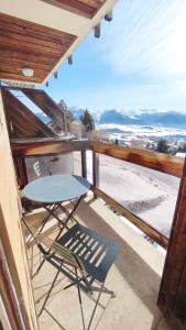 a table and a chair on the balcony of a house at Charmant Appartement Les temples du Soleil in Font-Romeu-Odeillo-Via
