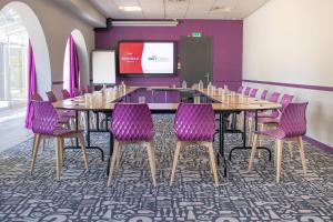 a conference room with a long table and purple chairs at Brit Hotel Nantes Vigneux - L'Atlantel in Vigneux-de-Bretagne