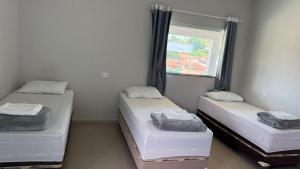 two twin beds in a room with a window at Hotel Serrinha in Botumirim