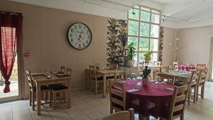 a dining room with tables and a clock on the wall at Carpe Diem 2 in Goutrens