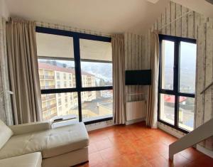 a living room with a couch and large windows at Apartamentos Gorbea Suites in Sierra Nevada