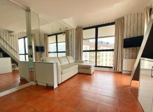 a living room with a white couch and large windows at Apartamentos Gorbea Suites in Sierra Nevada
