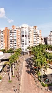 a street with palm trees in front of a large building at Atrium Studios by Xtay –Modern, Well-Located Studios, 9min from Arena Opus in Palhoça