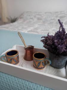 a tray with three cups and a vase with flowers at Soul in Bela Crkva +16 photos