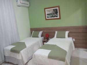 2 camas en una habitación con paredes verdes en Domus Hotel Torre Canaã dos Carajás, en Canaã dos Carajás