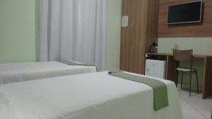 um quarto de hotel com duas camas e uma televisão em Domus Hotel Torre Canaã dos Carajás em Canaã dos Carajás