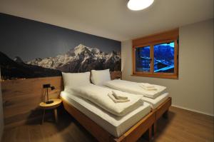 a bedroom with two beds and a mural of a mountain at Tossu, Haus Metropol B in Grächen