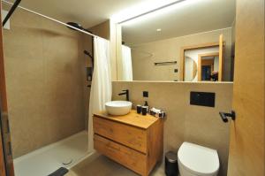 a bathroom with a sink and a toilet and a mirror at Tossu, Haus Metropol B in Grächen