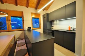 a kitchen with black countertops and wooden ceilings at Tossu, Haus Metropol B in Grächen