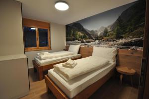 two beds in a room with a painting on the wall at Tossu, Haus Metropol B in Grächen