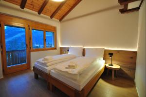 a bedroom with a bed with white sheets and a window at Tossu, Haus Metropol B in Grächen