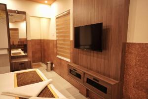 a bathroom with a flat screen tv on a wall at Kovilakam Achutham in Guruvāyūr