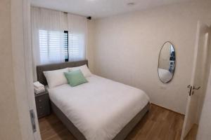 a bedroom with a white bed and a mirror at נוף לחרמון דפנה in Dafna