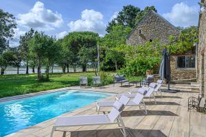 a swimming pool with white chairs and an umbrella at VILLA CALYPSO - Longère avec piscine vue mer in Noyalo