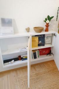a white book shelf with books on it at Quiet Forest-Side Apartment in Flamatt