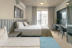 a hotel room with two beds and a desk at Moderno e Central - CA905 in Maringá