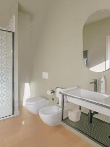 a white bathroom with a toilet and a sink at Unconventional Sorrento Coast in Sant'Agnello