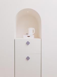 a white cabinet with a cup on top of it at Unconventional Sorrento Coast in Sant'Agnello