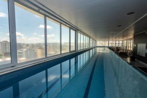 a swimming pool in a building with windows at Plaza São Rafael Hotel - Próximo ao Cais Embarcadero e Hosp Santa Casa in Porto Alegre
