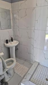 a white bathroom with a toilet and a sink at KeAnna STAYS units in Tsumeb