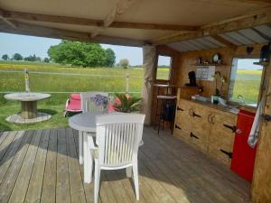 a wooden deck with a table and chairs and a kitchen at La chevauchée vers les étoiles in Yèvres