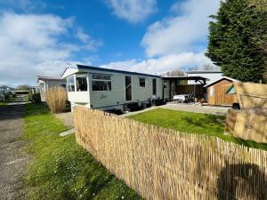 a caravan parked in a yard with a fence at Beach Resort Kamperland - 1747 in Kamperland