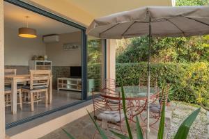 a patio with a table and an umbrella at Les Sarments in Le Lavandou