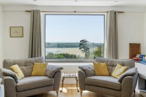 a living room with two chairs and a large window at Beautiful Home with Pool Overlooking Camel Estuary in Roche