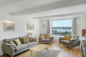 a living room with two couches and a large window at Beautiful Home with Pool Overlooking Camel Estuary in Roche +29 photos