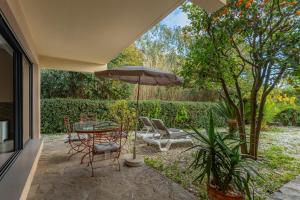 a patio with a table and chairs and an umbrella at Les Sarments in Le Lavandou