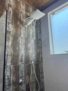 a shower with a shower head in a bathroom at Casa das Palmeiras in Imbituba