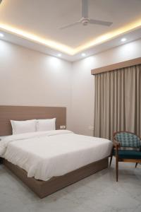a bedroom with a large bed and a chair at Old RAO Hotel Kotwan in Kosi