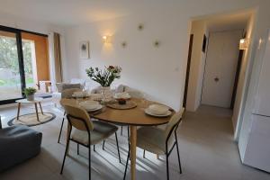 a dining room with a wooden table and chairs at Casa 115 - Plage & piscine chauffée in Pianottoli-Caldarello