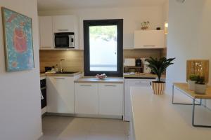 a kitchen with white cabinets and a window at Casa 115 - Plage & piscine chauffée in Pianottoli-Caldarello