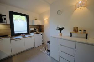 a kitchen with white cabinets and a flat screen tv at Casa 115 - Plage & piscine chauffée in Pianottoli-Caldarello