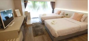 a bedroom with two beds and a desk with a television at Luna hotel in Gua Sai