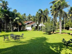a yard with a table and chairs and palm trees at Dark Green Resort - Airport Transit Villa in Negombo