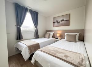 two beds in a room with a window at Mobile Homes Relax Park Umag in Umag +20 photos