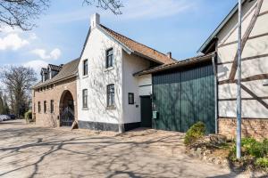 a white house with a green garage at boerderij, voorhuis in Schimmert