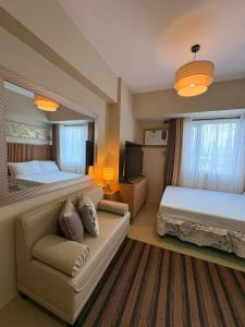 ein Hotelzimmer mit zwei Betten und einer Couch in der Unterkunft KBrothers - Chic Studio in the Heart of it All! in Cagayan de Oro